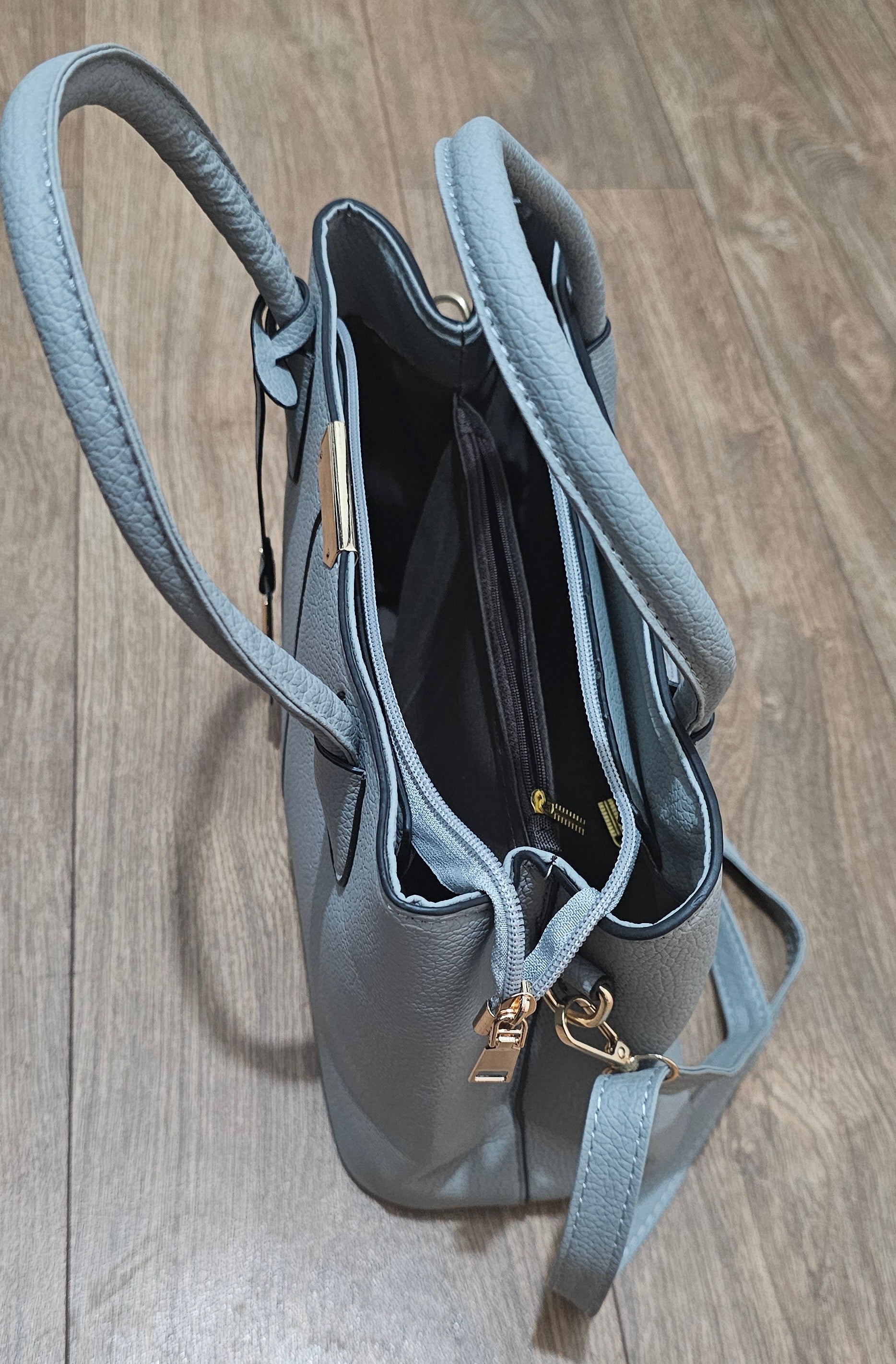 Light blue handbag with gold hardware on a wooden surface