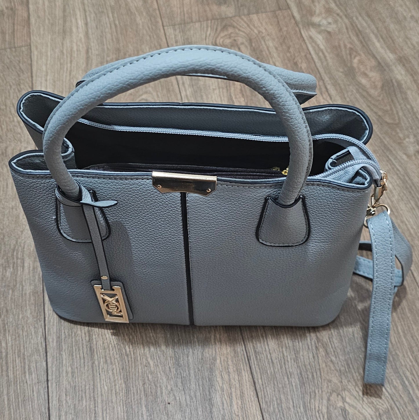 Gray handbag with a strap on a wooden surface