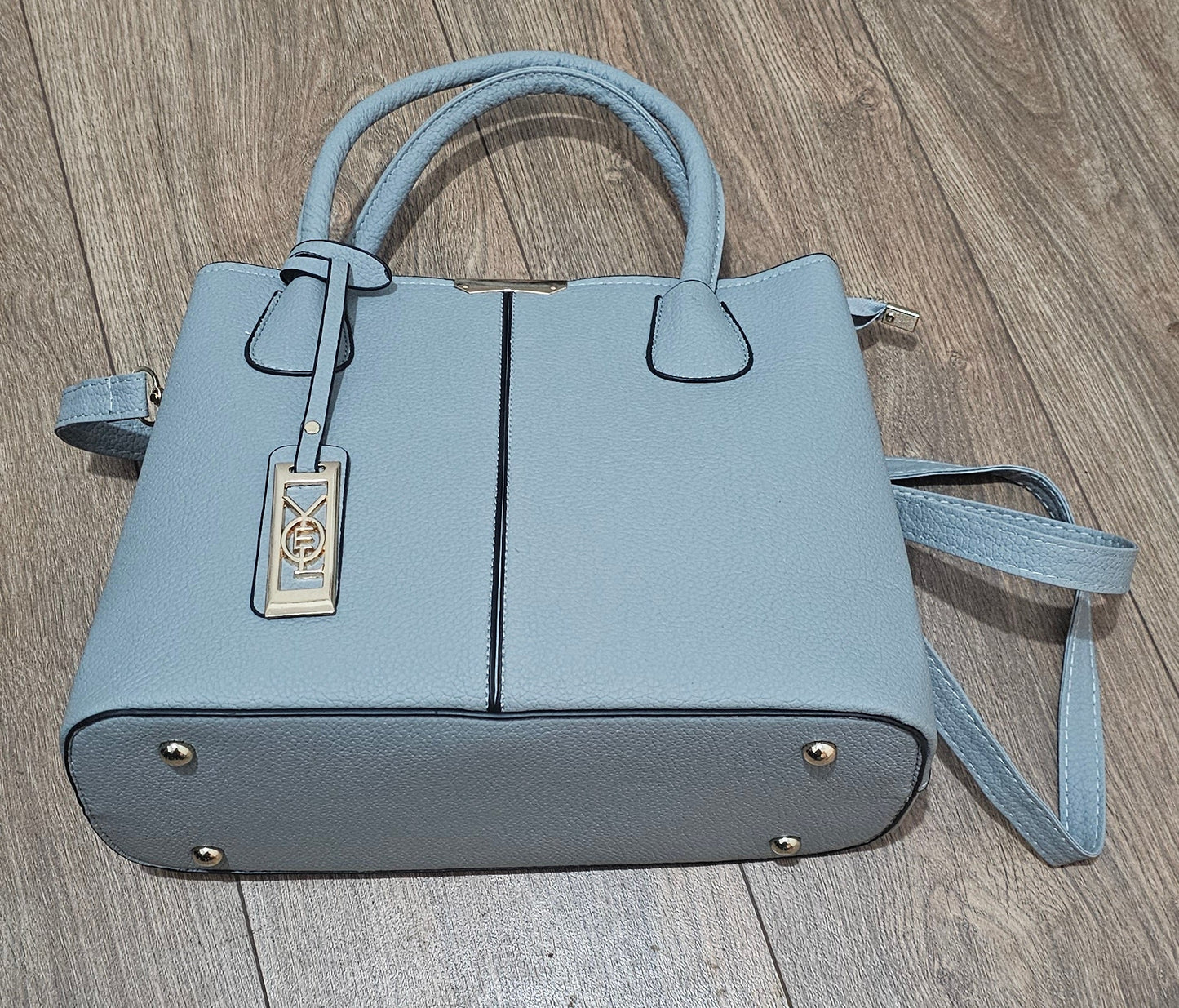 Light blue handbag with a strap on a wooden surface