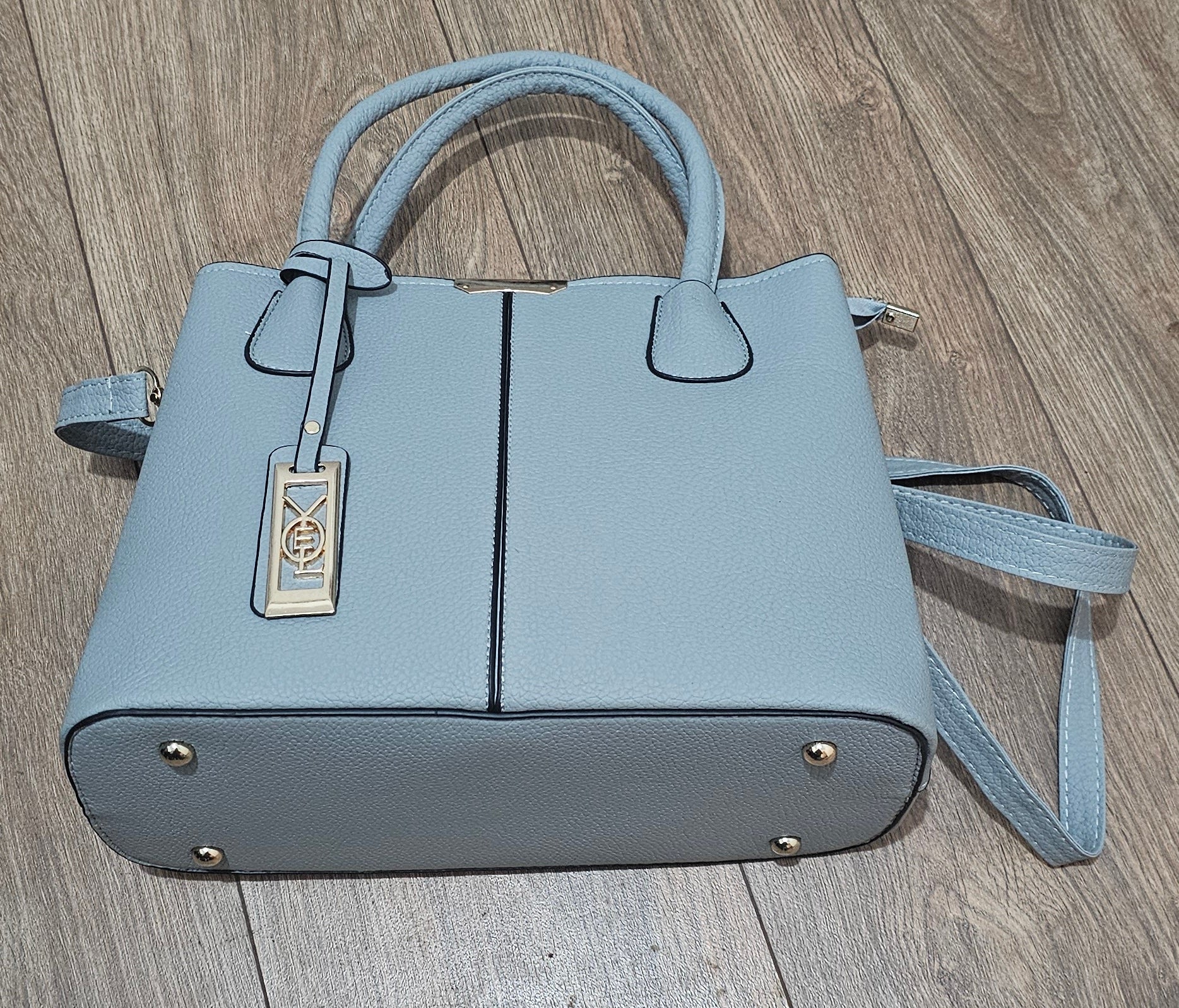 Light blue handbag with a strap on a wooden surface
