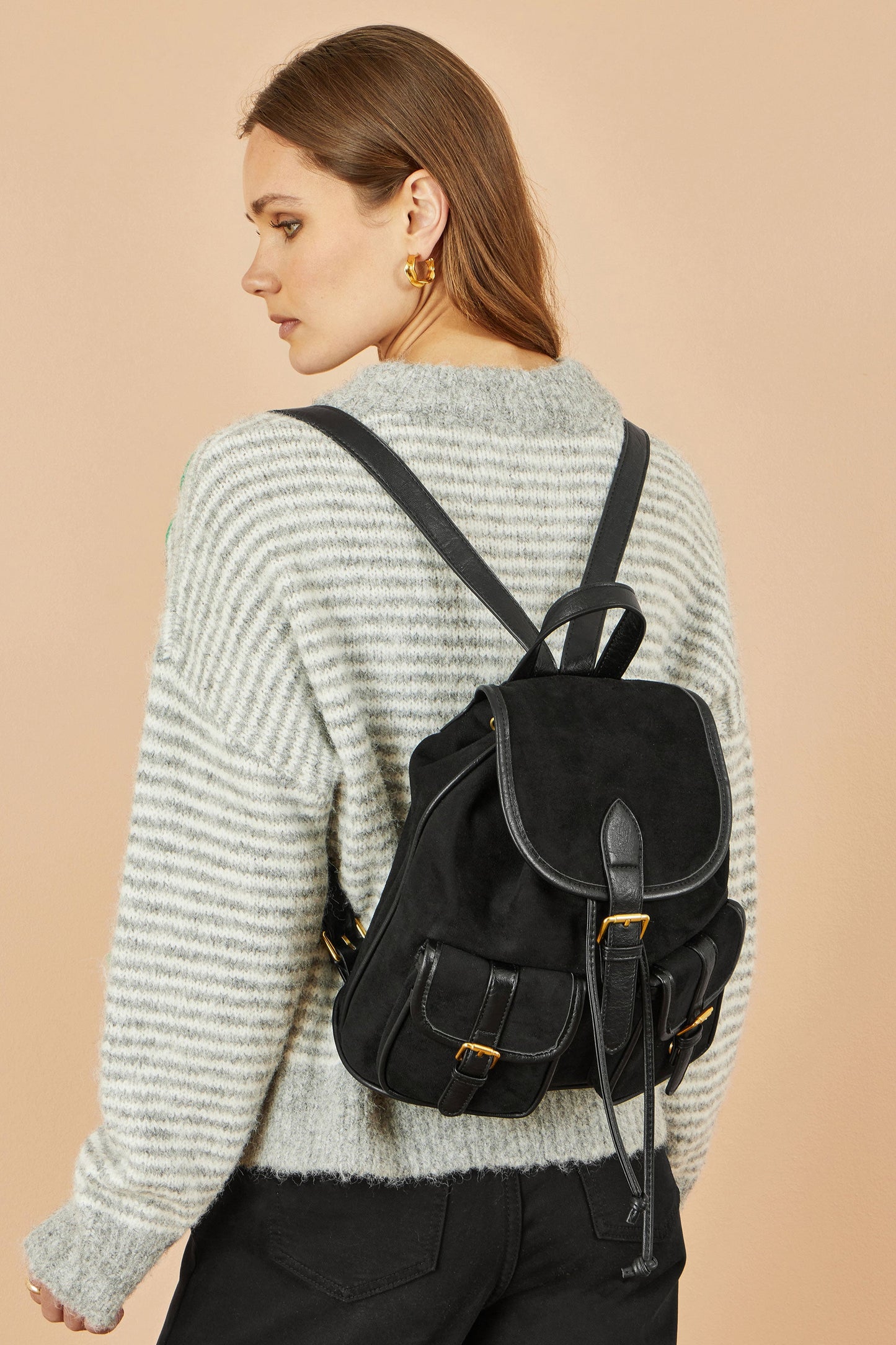 Woman wearing a black backpack on a beige background