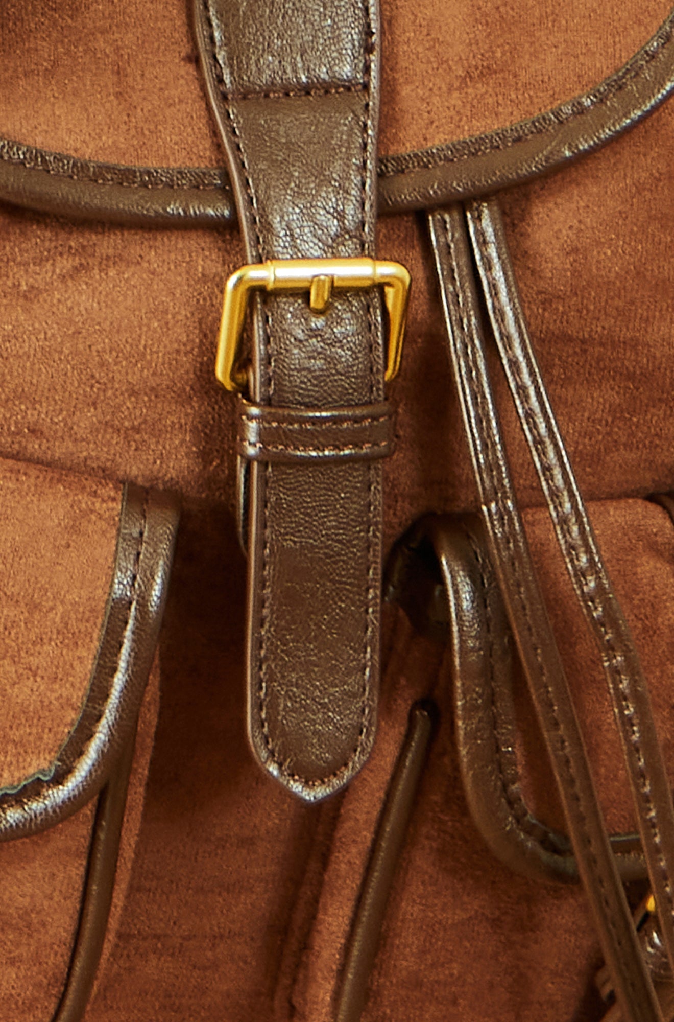 Close-up of a brown leather backpack with a gold buckle.