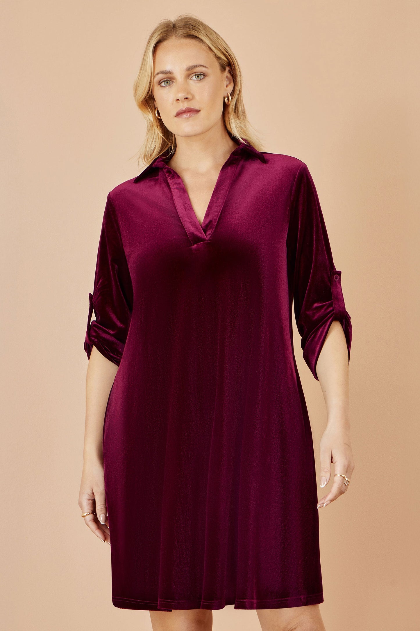 Woman wearing a burgundy dress against a beige background