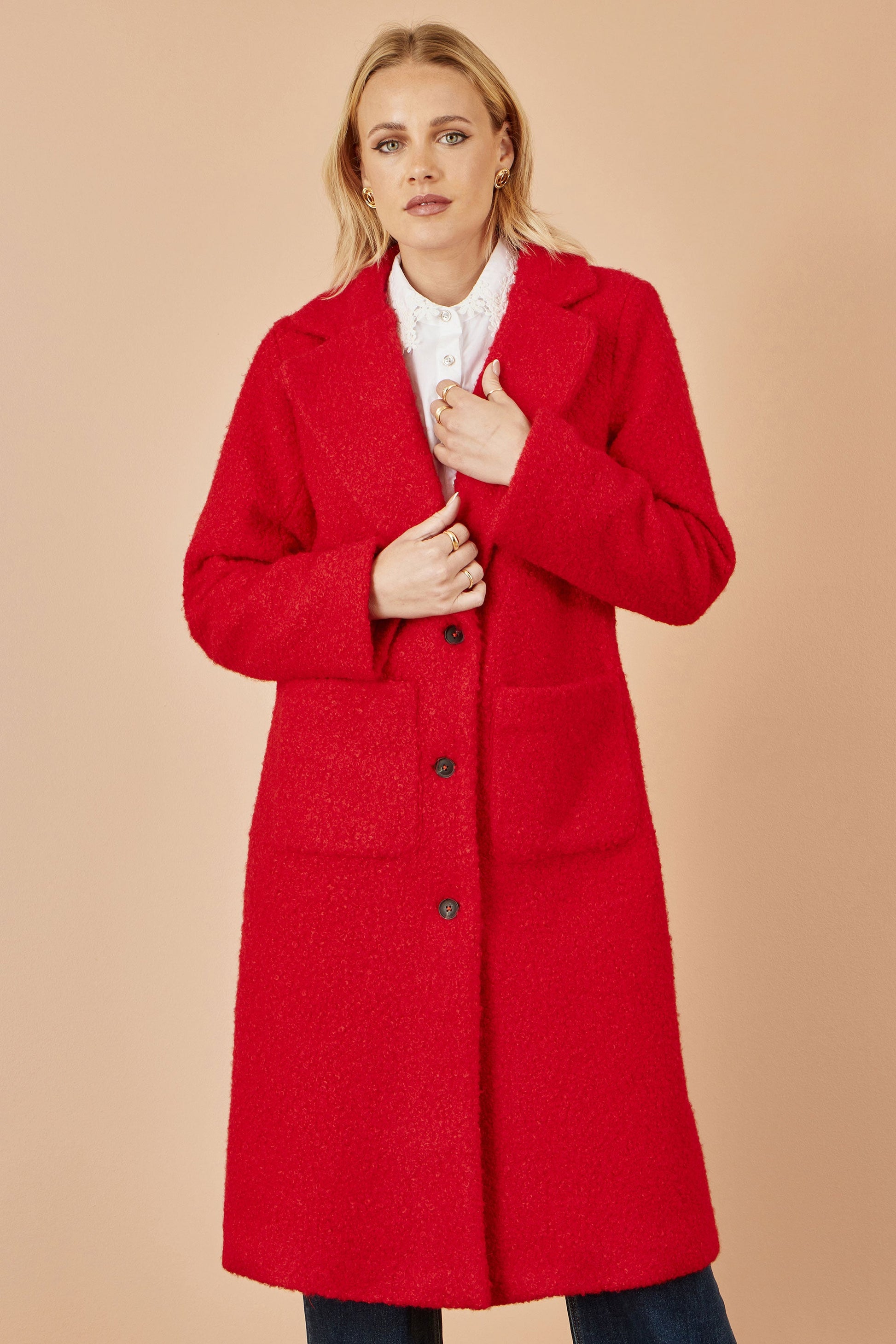 Woman wearing a red coat against a beige background