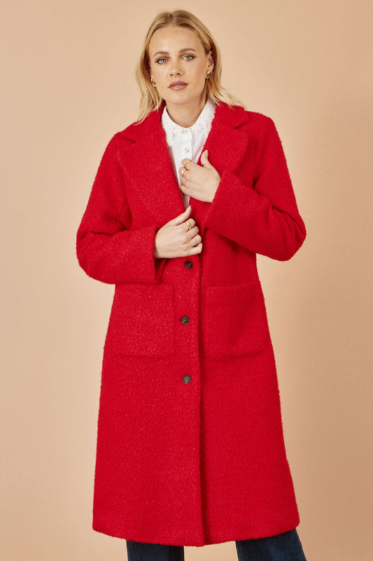 Woman wearing a red coat against a beige background
