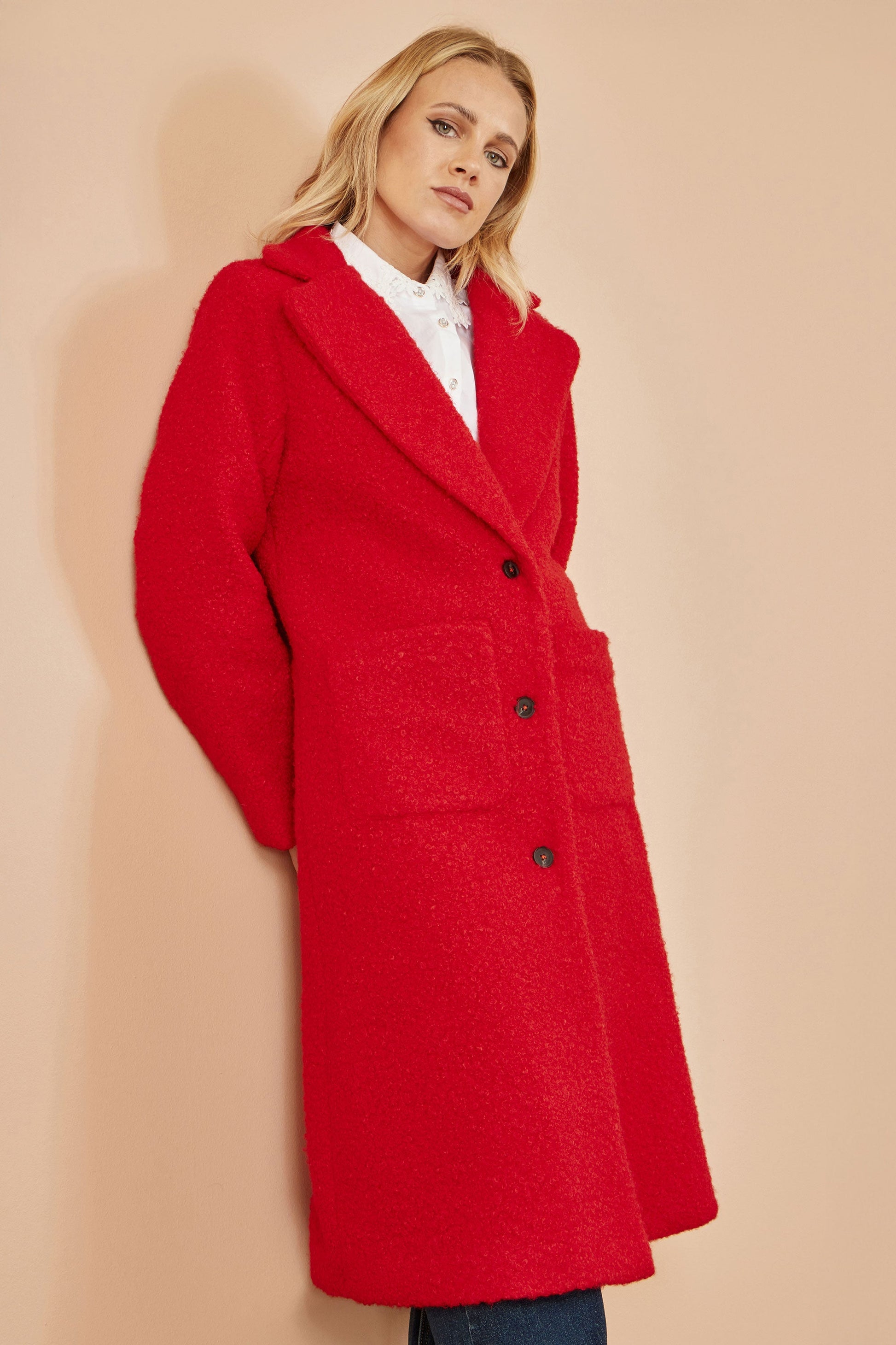 Woman wearing a red coat against a beige background