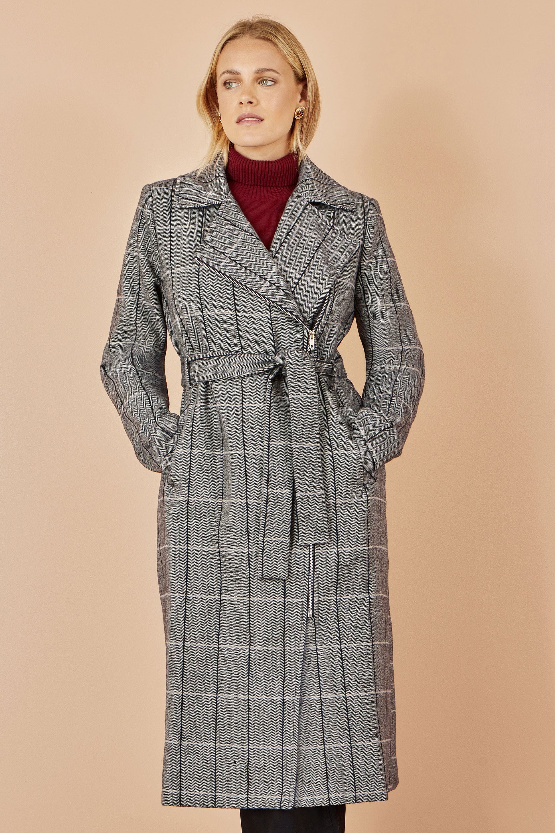 Woman wearing a gray checkered coat against a beige background