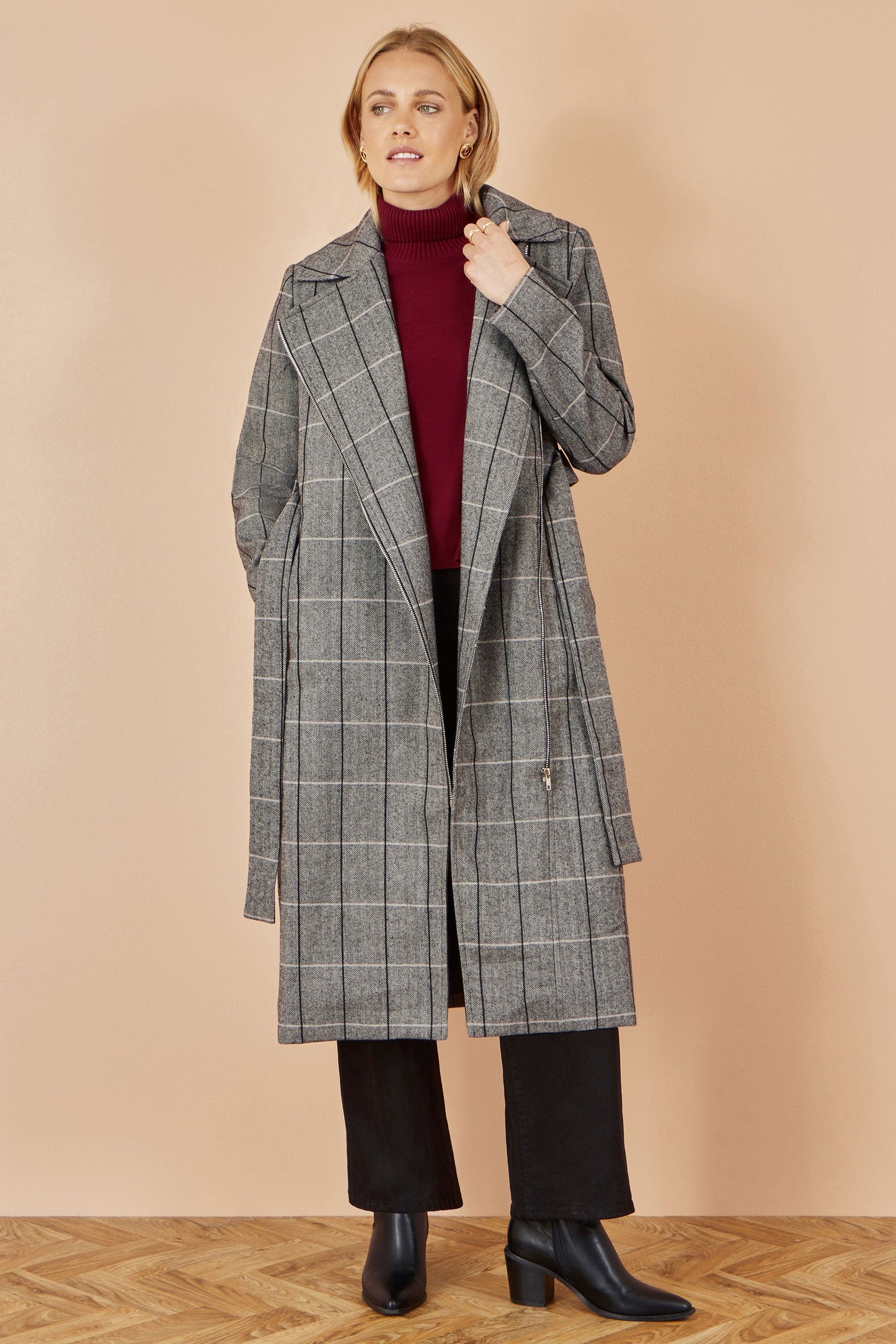 Woman wearing a gray checkered coat on a beige background