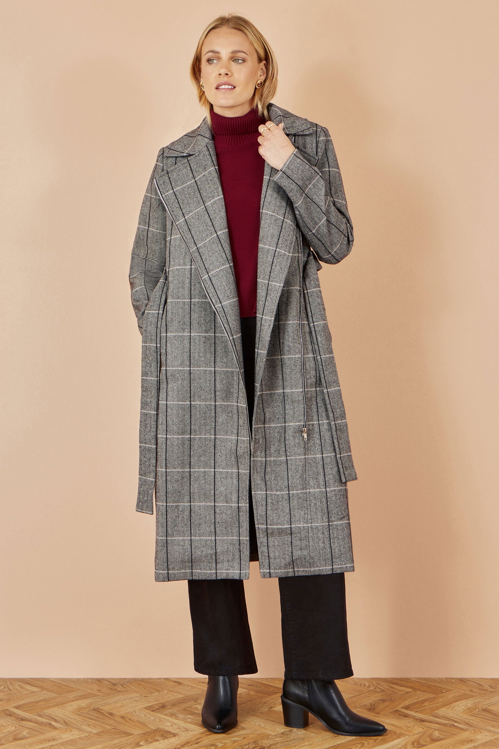 Woman wearing a gray checkered coat on a beige background