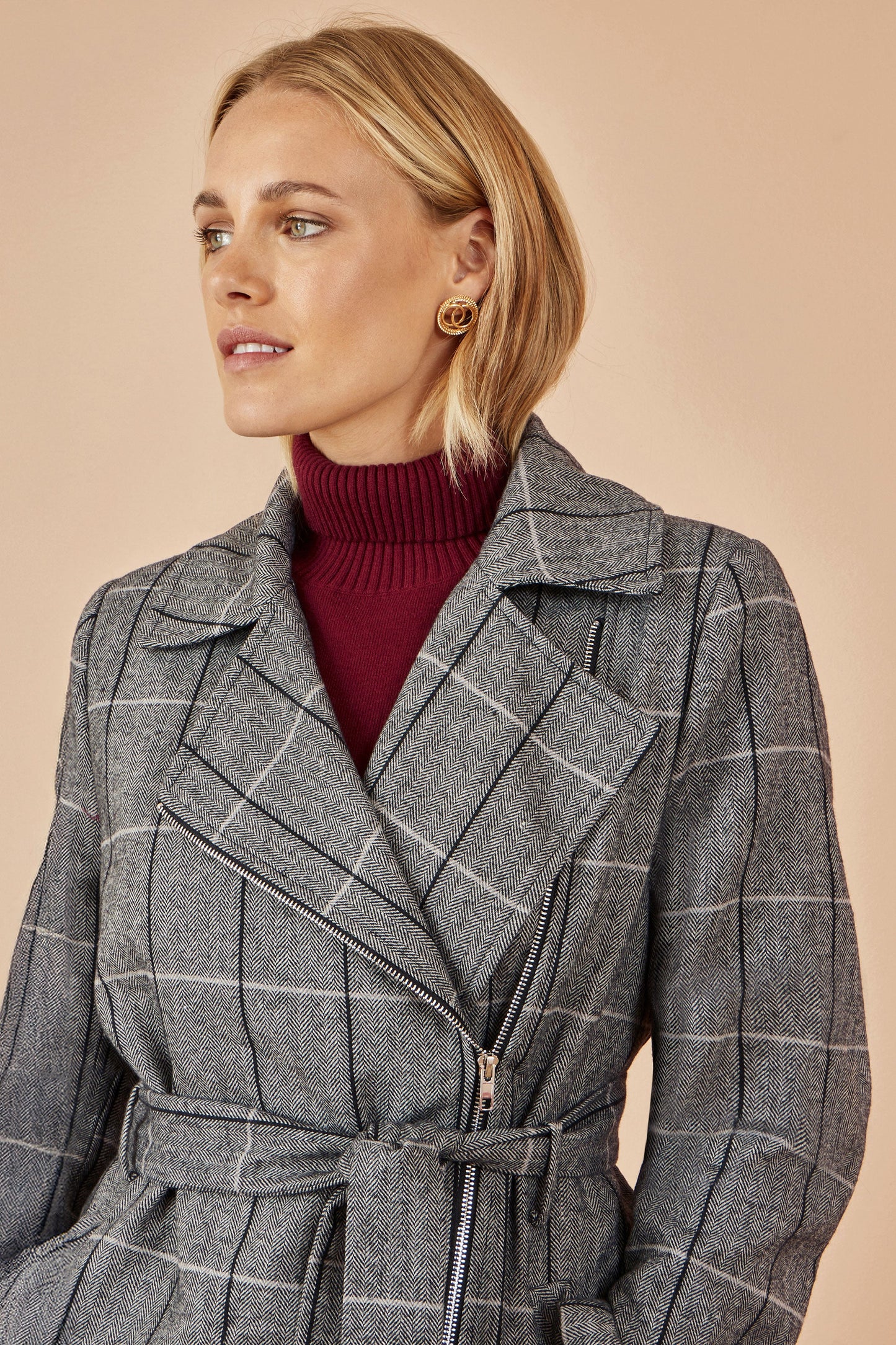 Woman wearing a gray checkered coat with a beige background