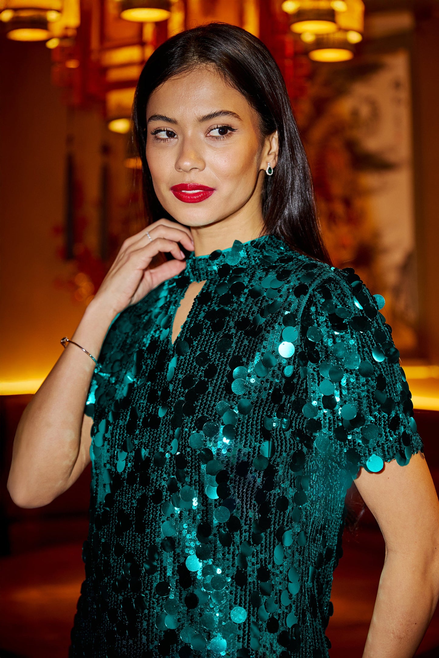 Woman wearing a green sequin dress in an indoor setting