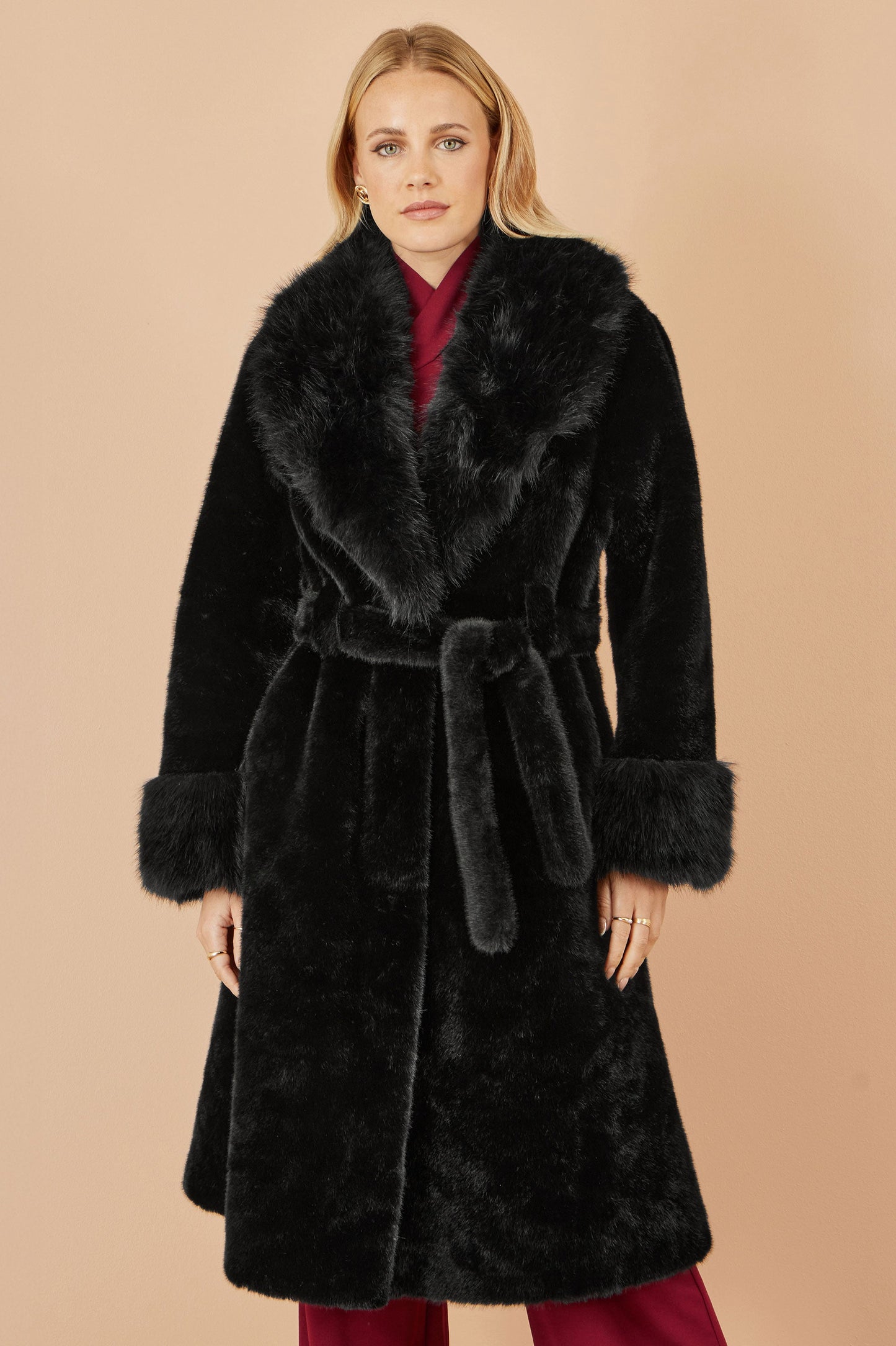 Woman wearing a black fur coat with a beige background