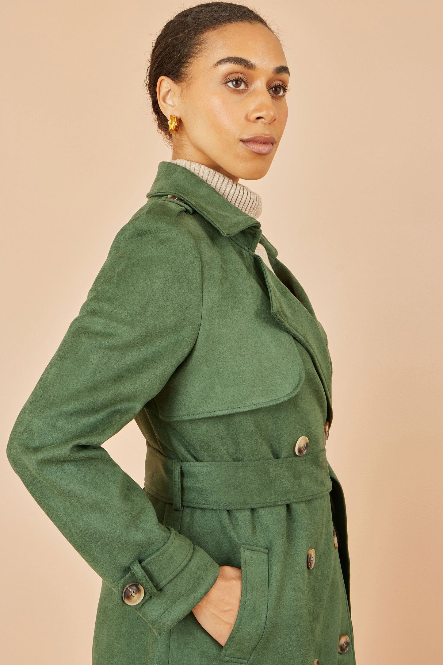 Woman wearing a green coat against a beige background