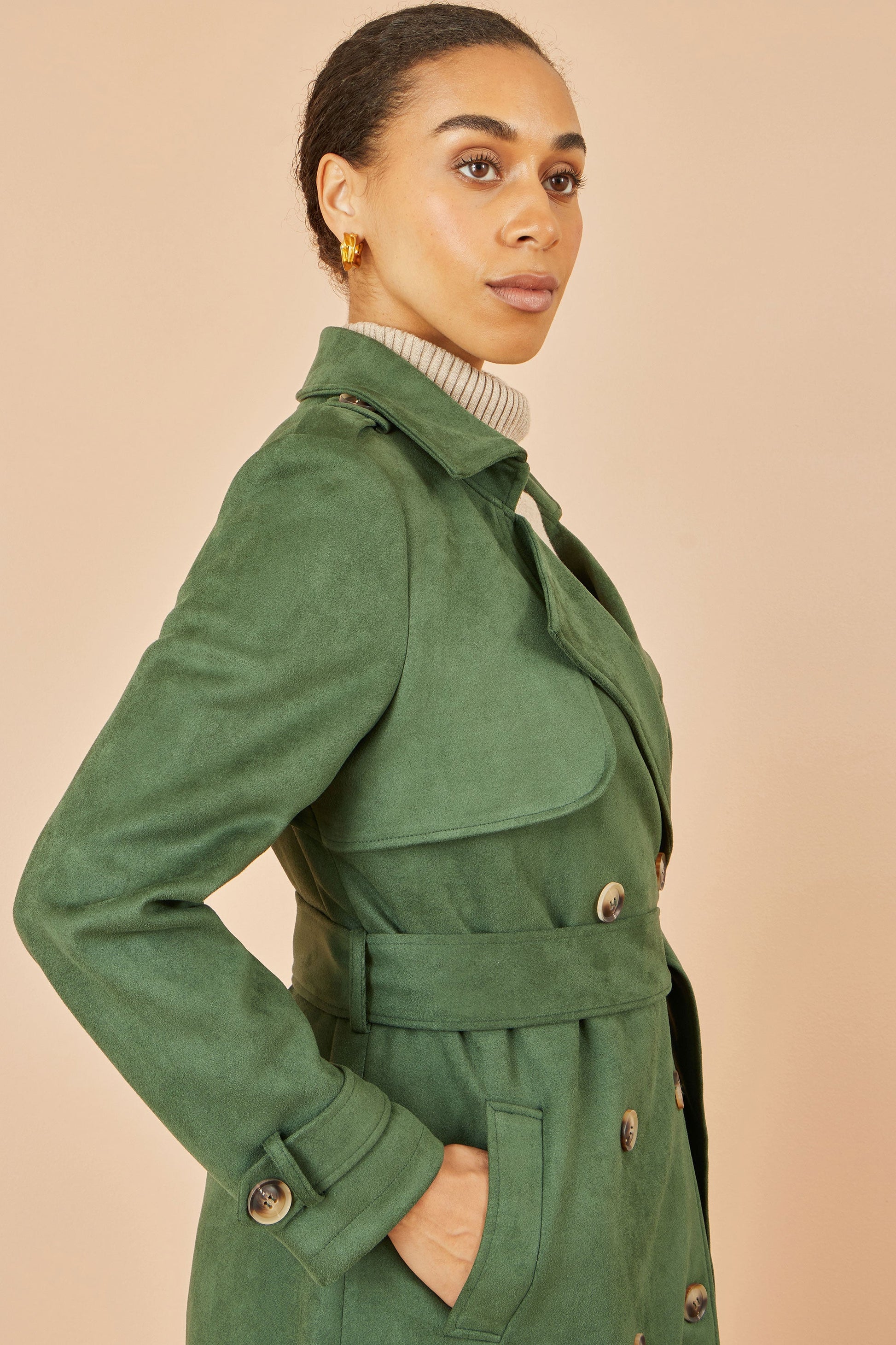 Woman wearing a green coat against a beige background