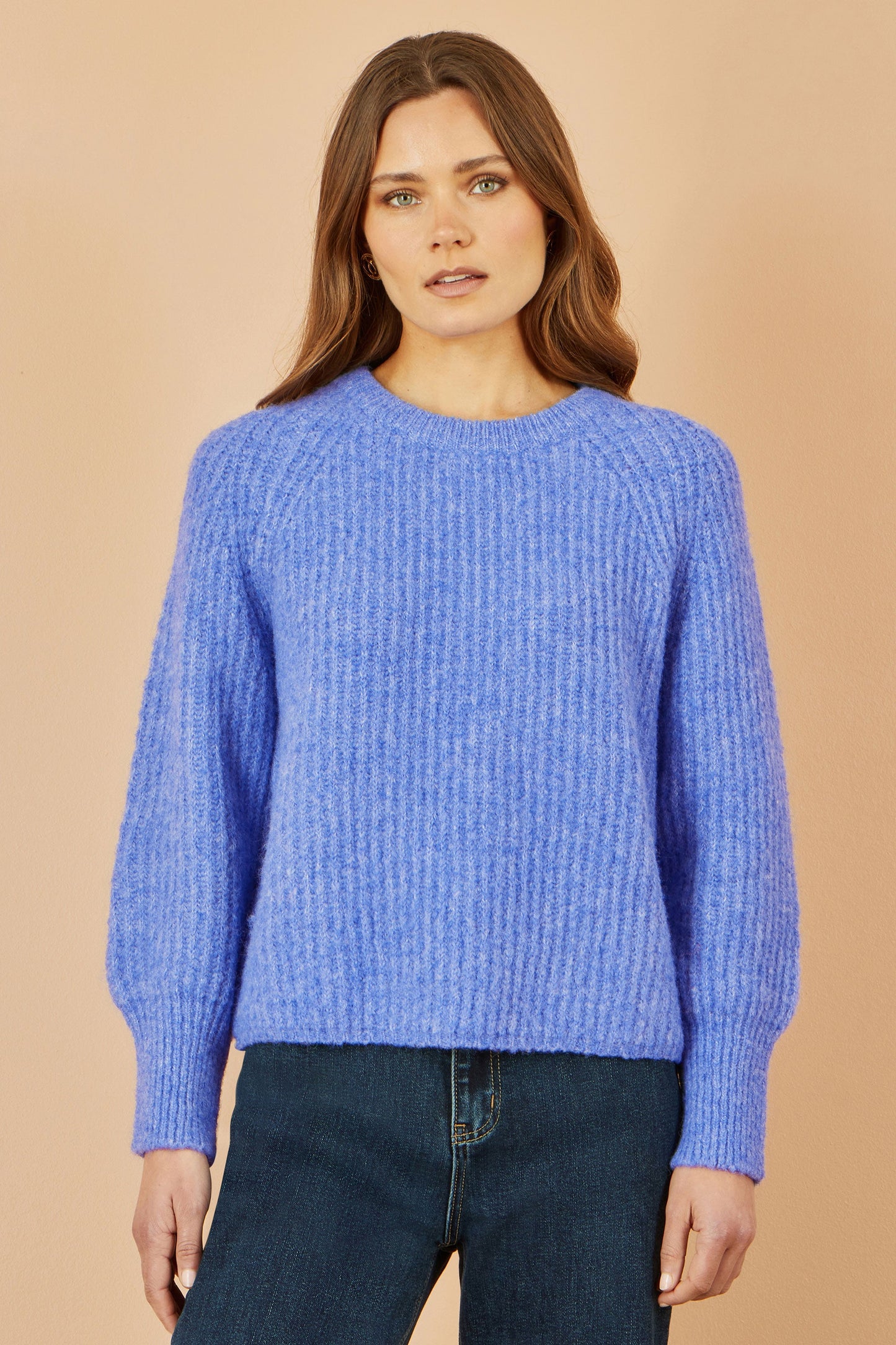 Woman wearing a blue sweater against a beige background