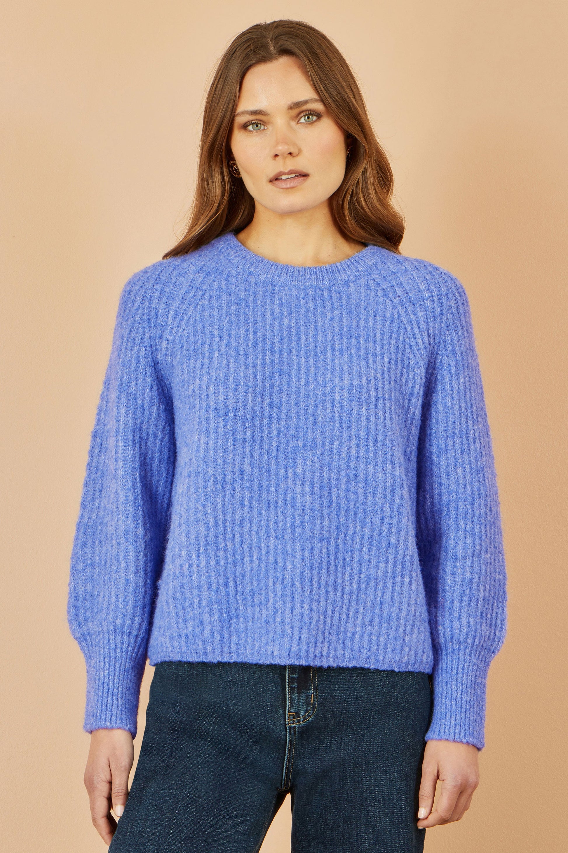 Woman wearing a blue sweater against a beige background
