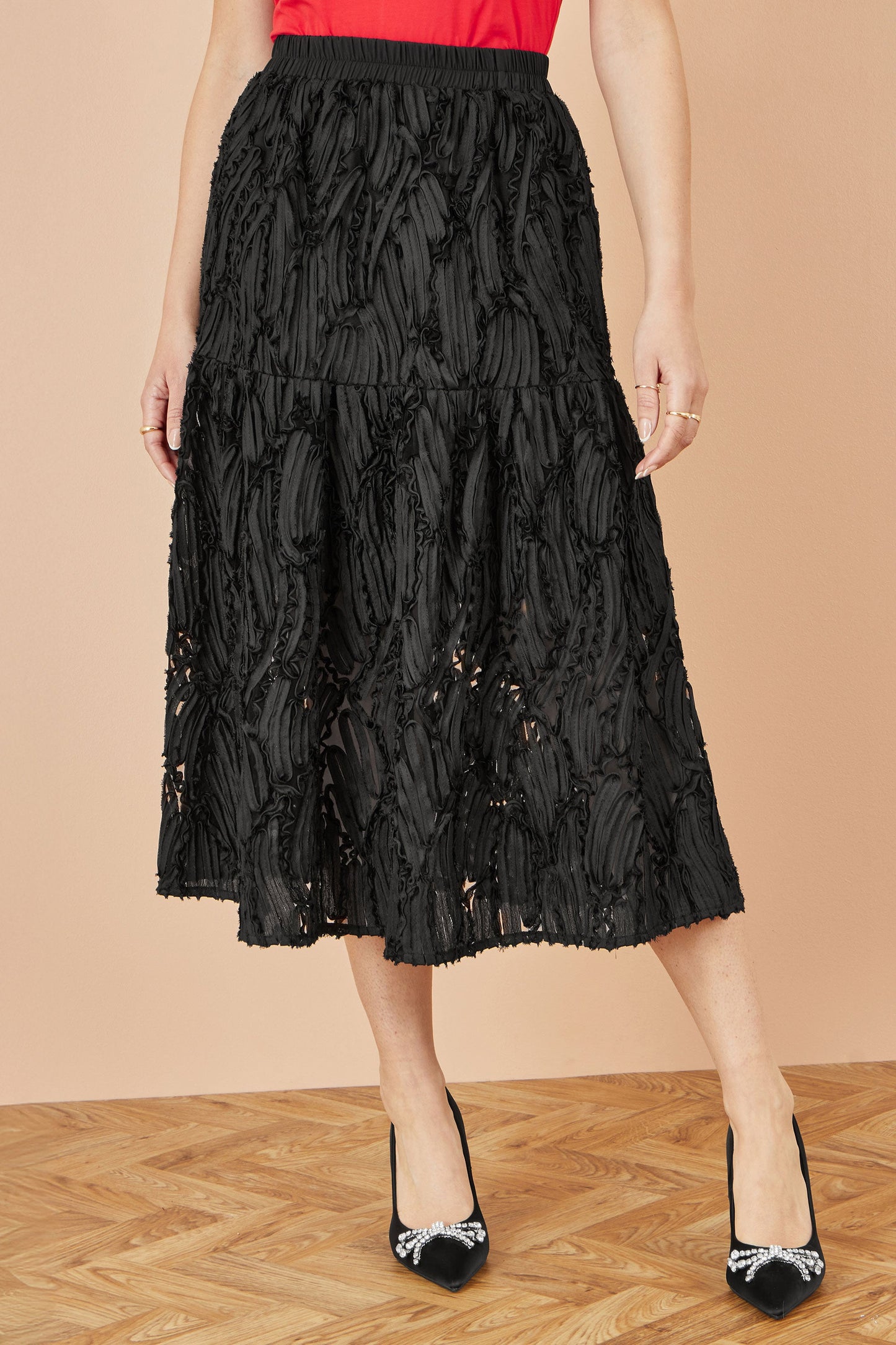 Black lace skirt worn by a person on a beige background