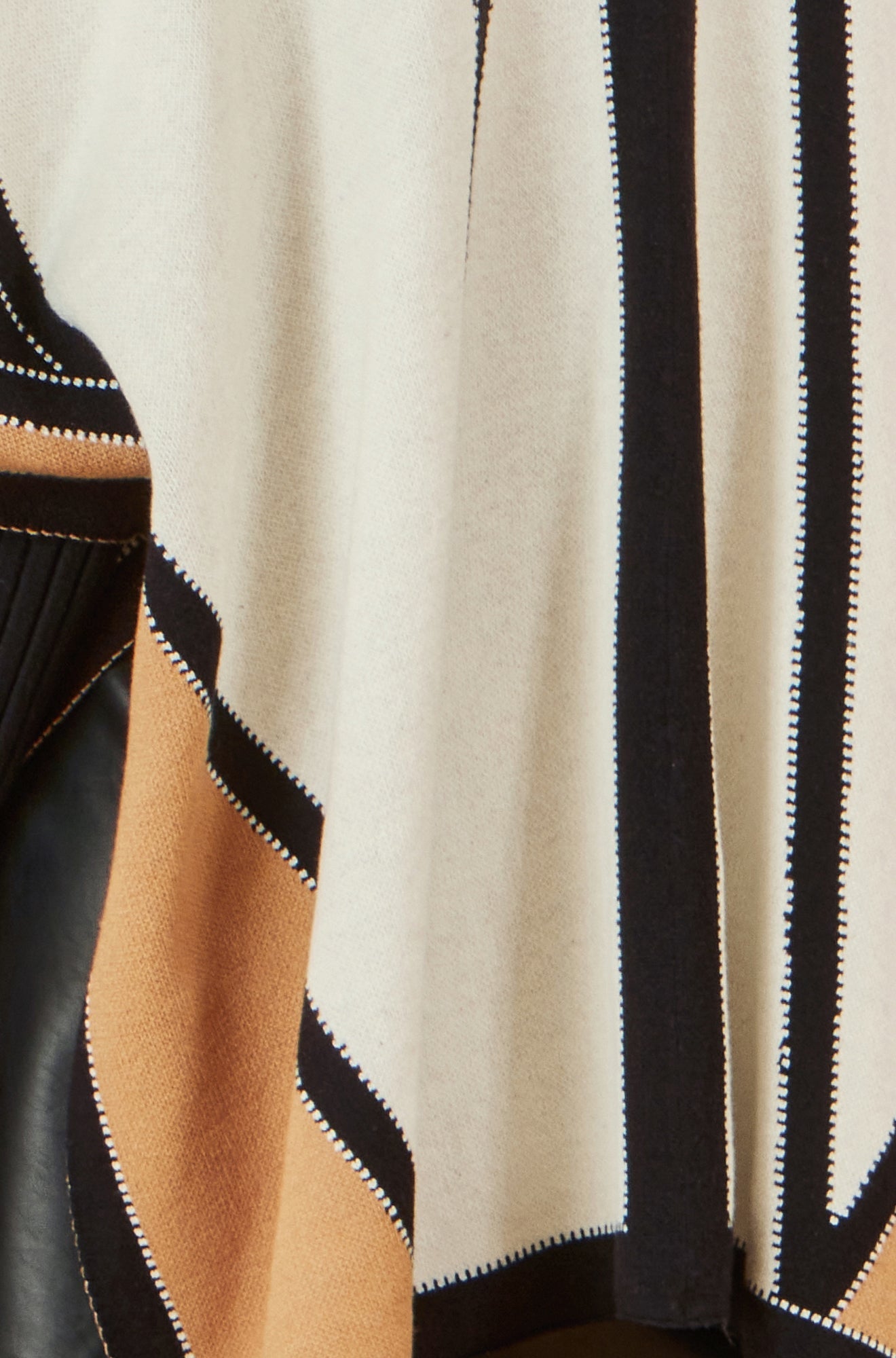 Close-up of a garment with black, beige, and white stripes.