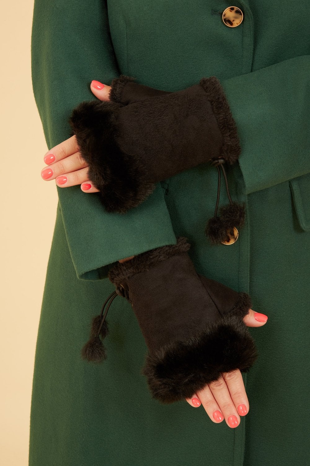 Person wearing black fingerless gloves with fur trim against a green coat.