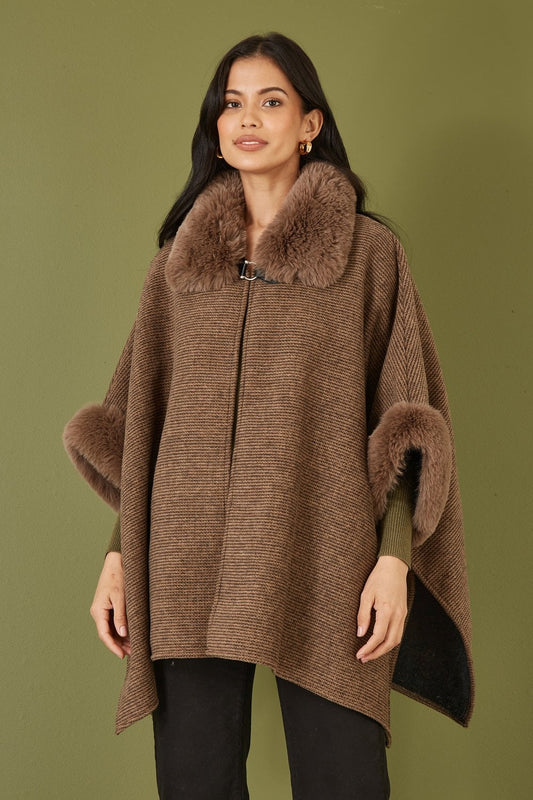 Woman wearing a brown poncho with fur trim against an olive green background