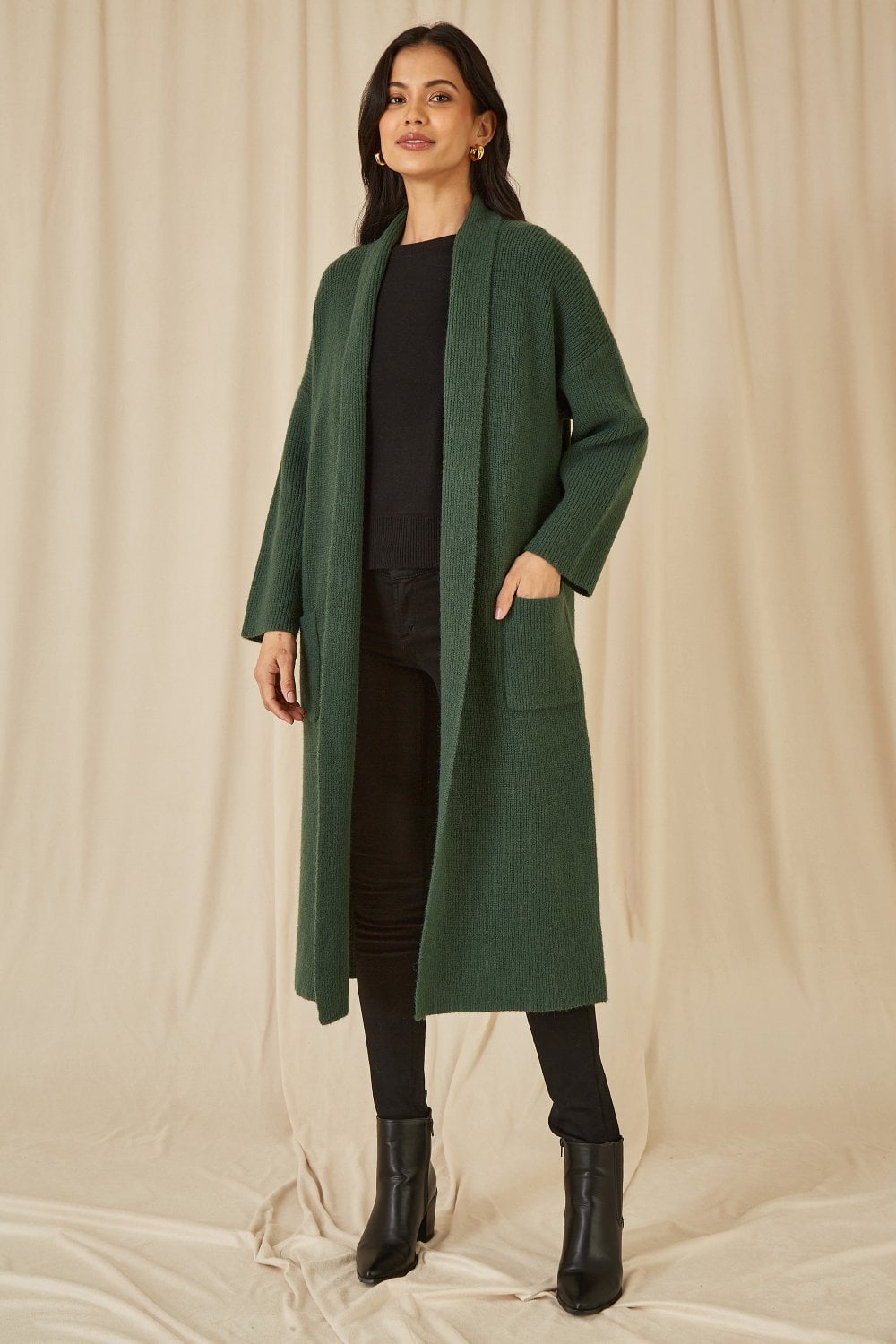 Woman wearing a green coat against a beige background